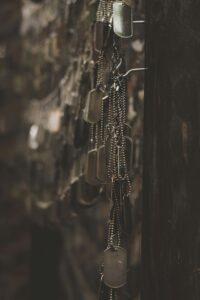 This is a picture of an unknown number of metal, military dog tags hanging on a black wall.