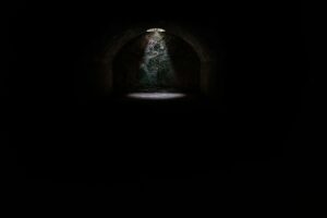 This is a picture of almost all darkness. The only exception is a whole at the top where light is shining through and is reflected on the floor.