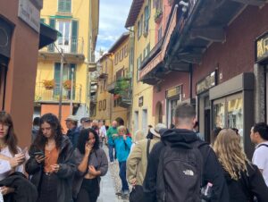 This is a picture of a street in Italy. There are colorful buildings on either side of the street, and the street is crowded with people. This is one of the towns we carried our luggage in on our vacation to Italy.