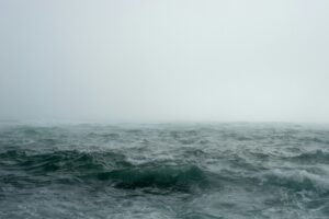 This is a picture of a dark grayish blue body of water with a lot of waves. The sky is a lighter gray, and it looks like a storm may be approaching.